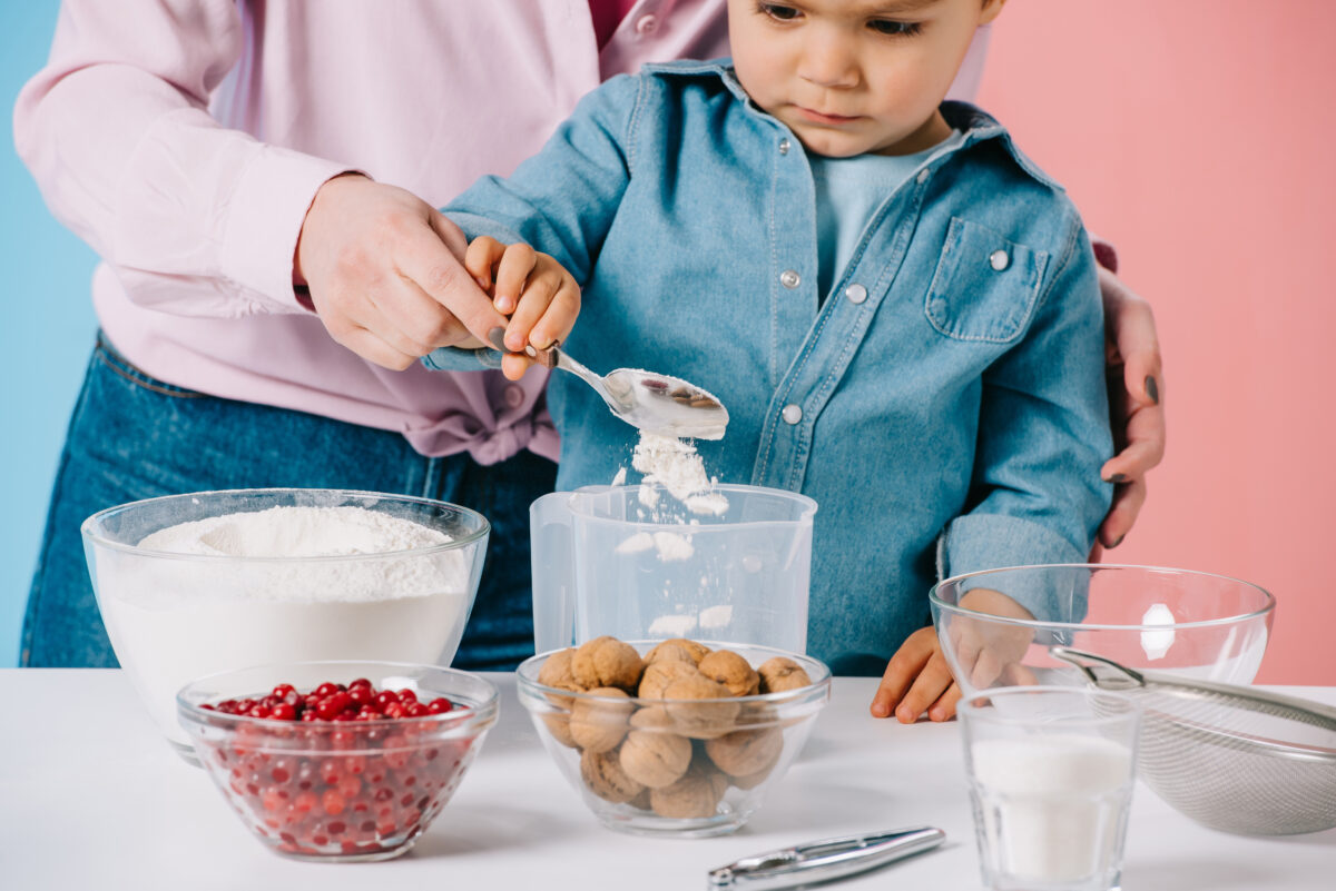 Mother and preschooler measuring baking ingredients in a fun math activity. 