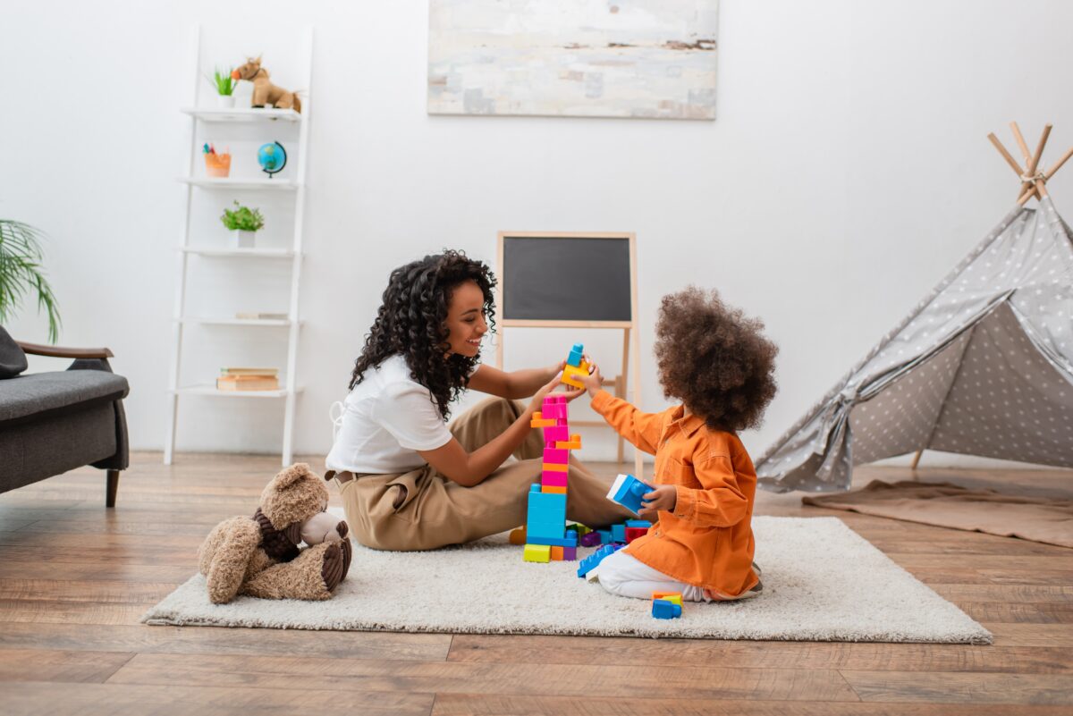 Mother and preschooler having fun playing with blocks. 