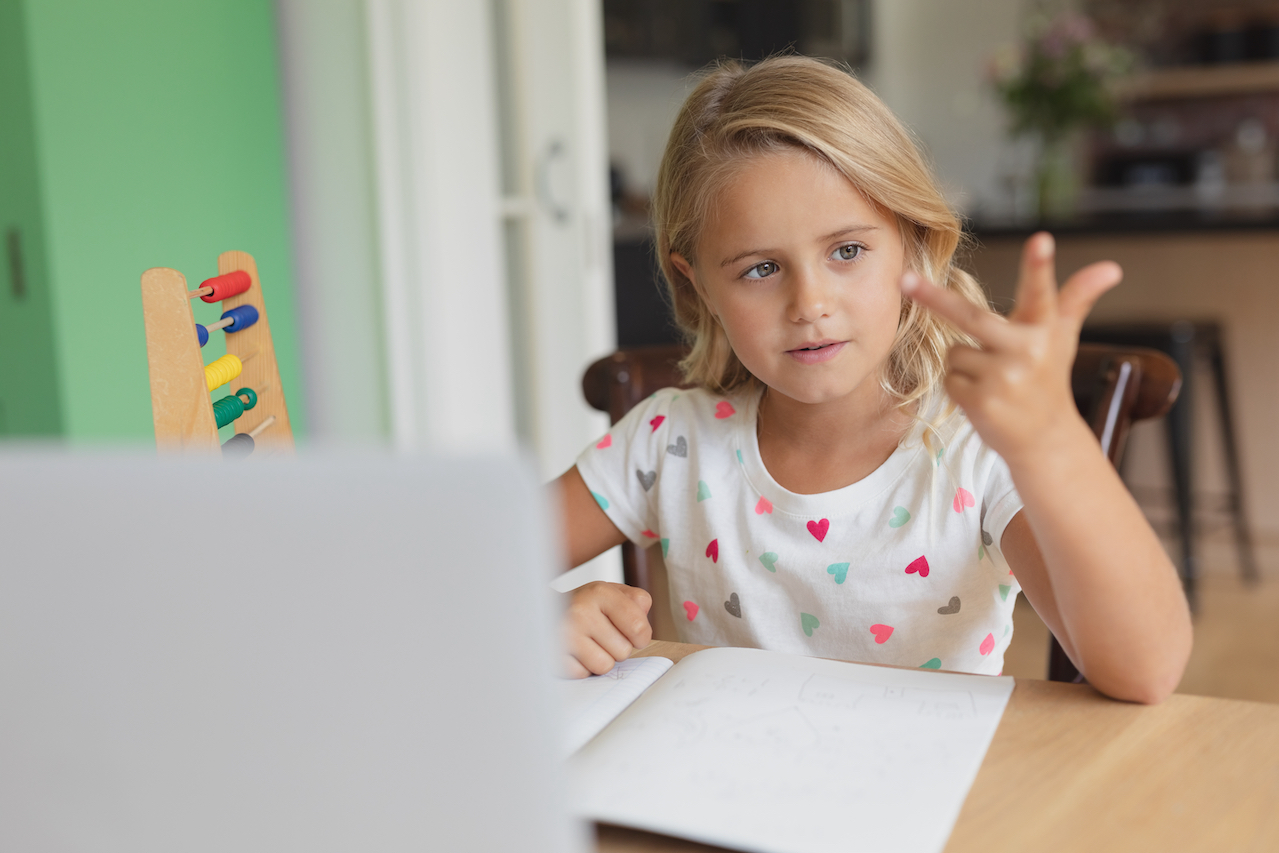 Front view of Caucasian girl doing homework at table in a comfortable home