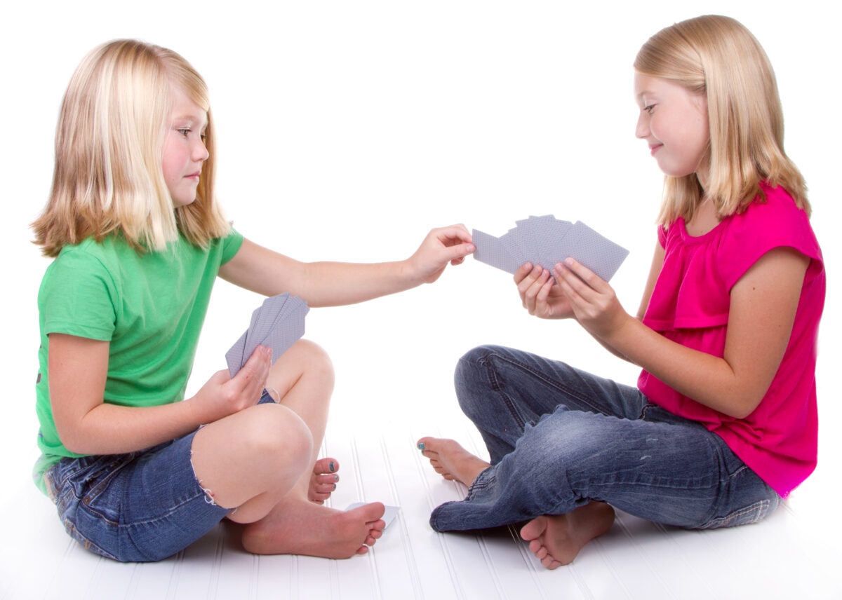 Two girls playing go-fish together. 