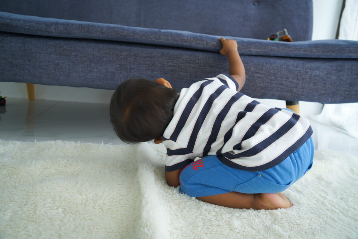 Boy looking under the couch. 