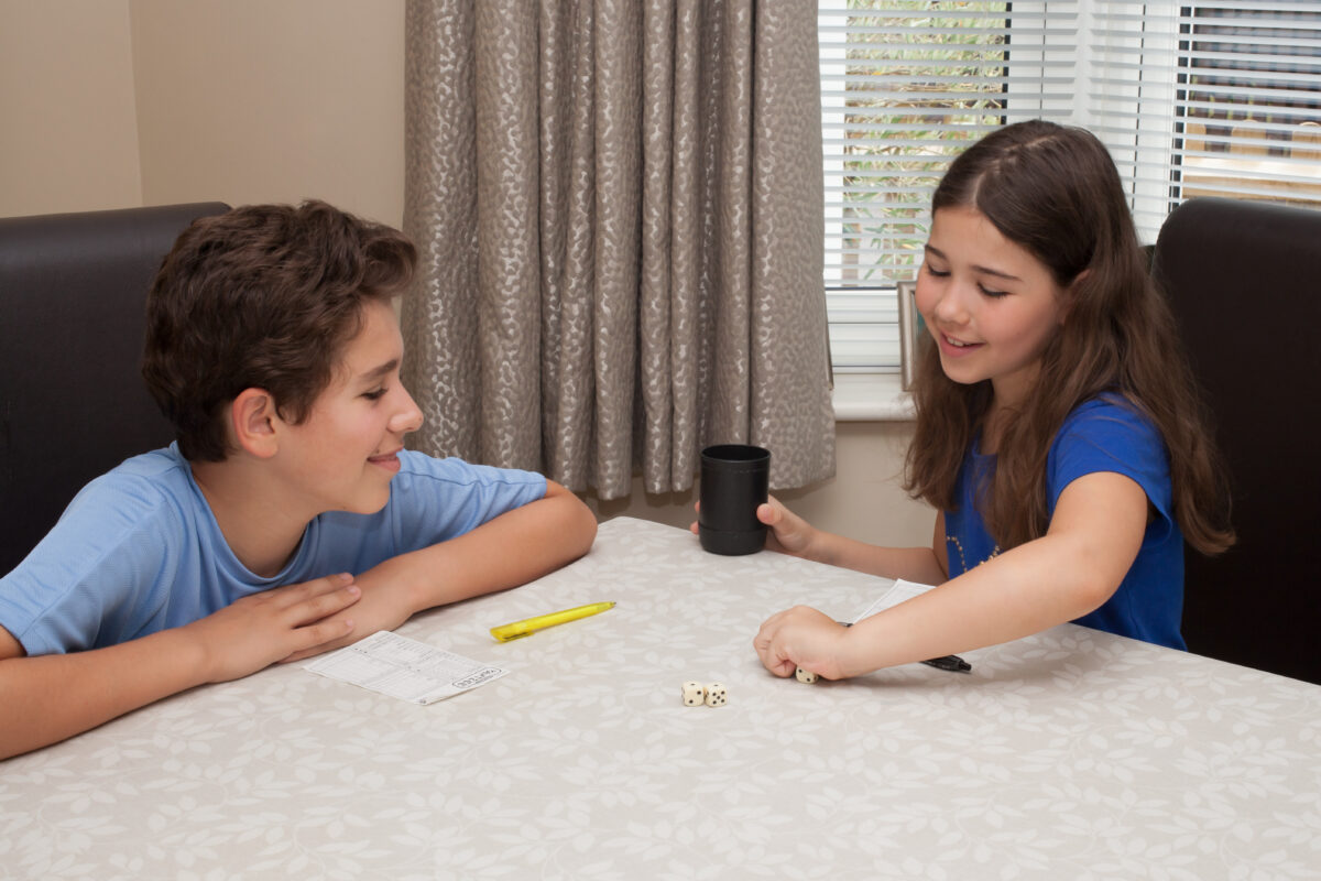 Children rolling a dice playing a reading game. 