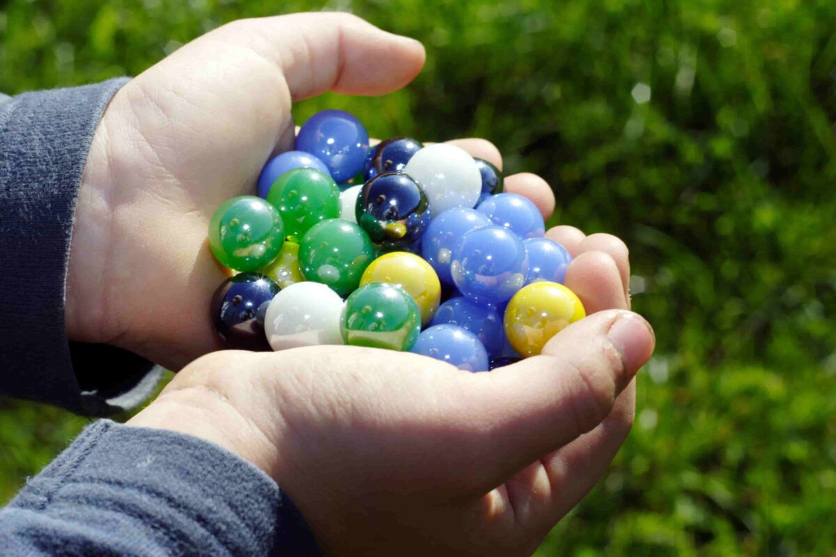 Child holding a handful of marbles. 