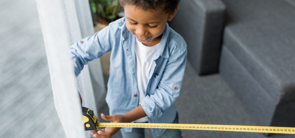 Boy with tape measure, practicing math activities. 