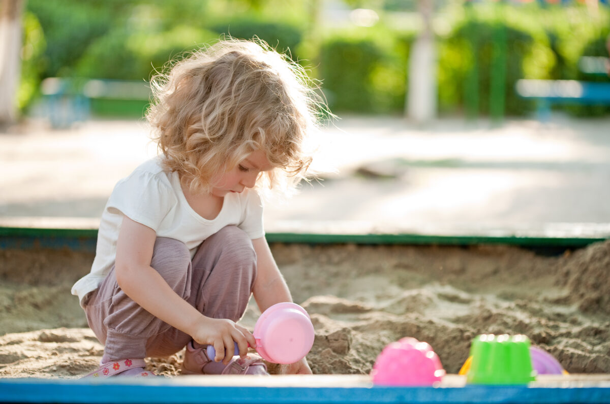 preschooler digging in the sand trying to find letters. 