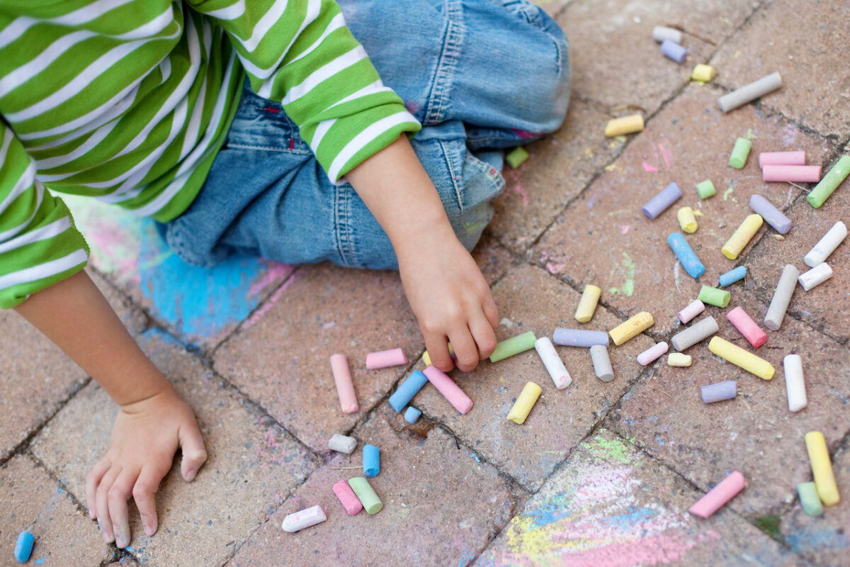 Child coloring on the pavement with chalk. 