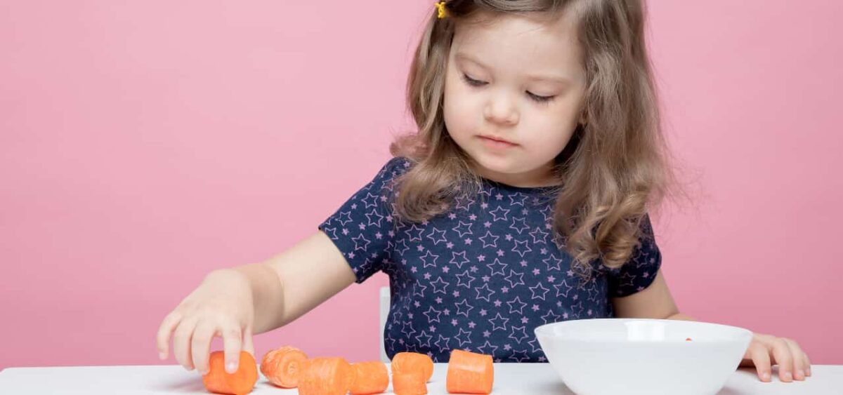 Preschooler counting pieces of carrots. 