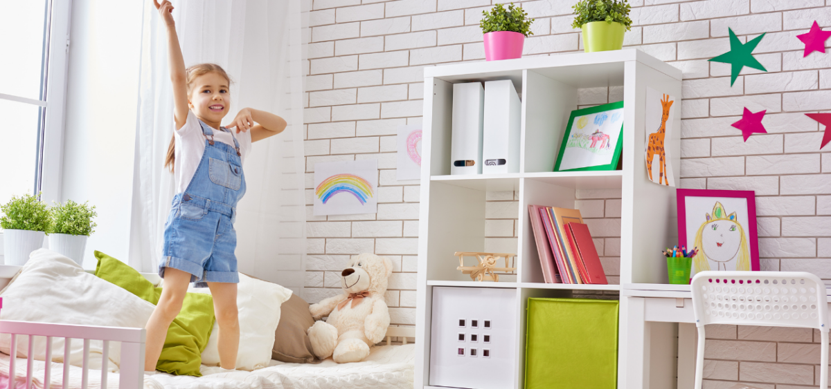 Preschooler standing on her bed with her arm in the air proud of herself for cleaning her room. 