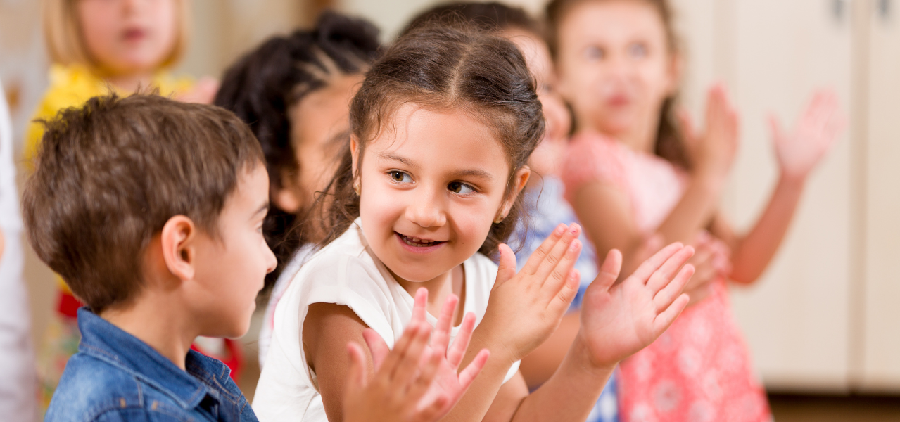 Kindergarten children clapping and singing together. 