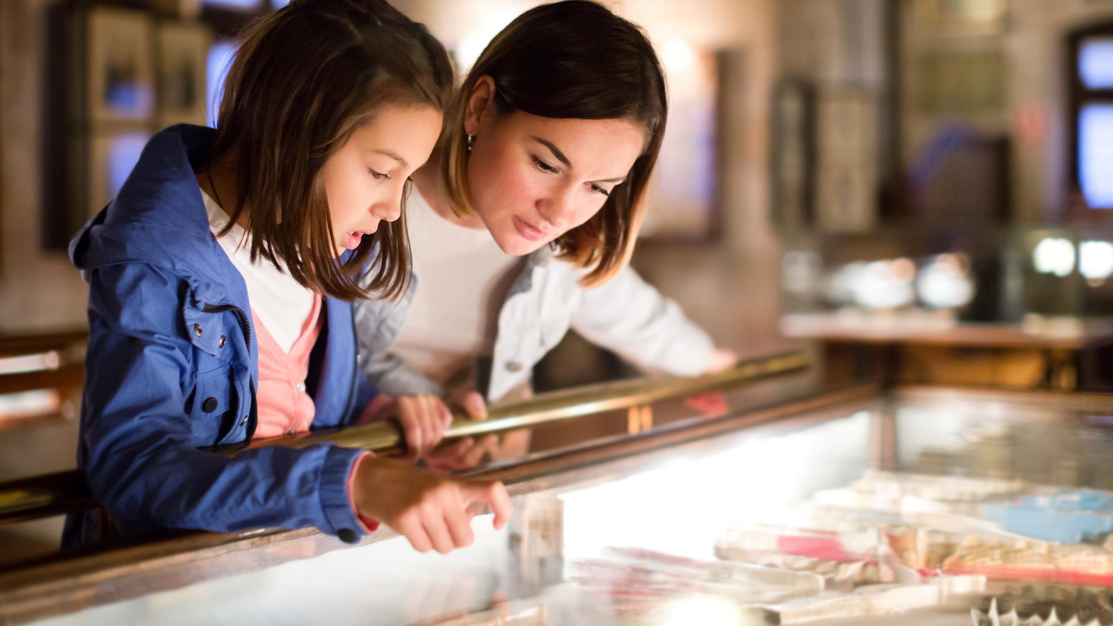 Mother and daughter looking at an exhibit at a museum together.