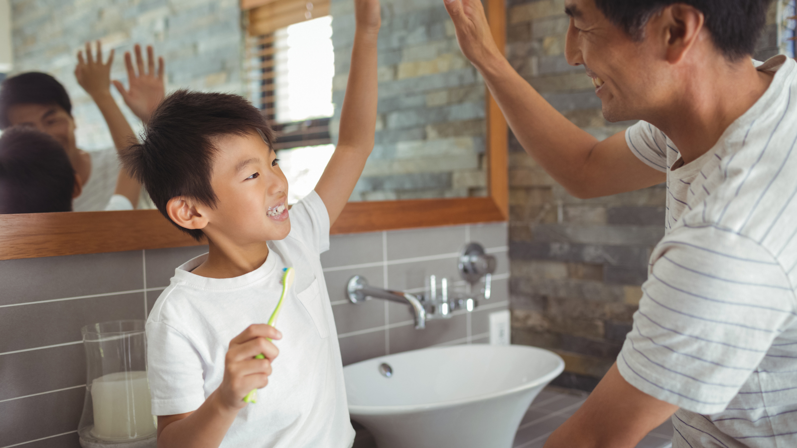 Dad high fiving his son for brushing his teeth.