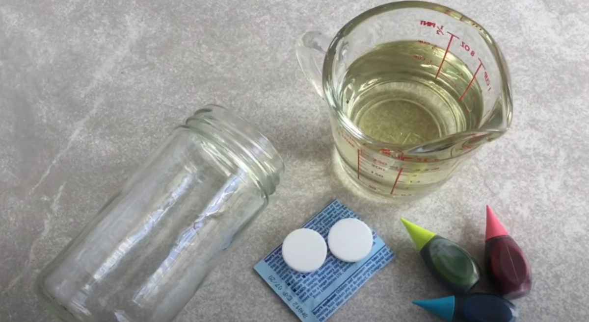 Supplies needed for a DIY Lava Lamp Science Activity. A glass jar, cooking oil, food coloring, and effervescent tablets. 