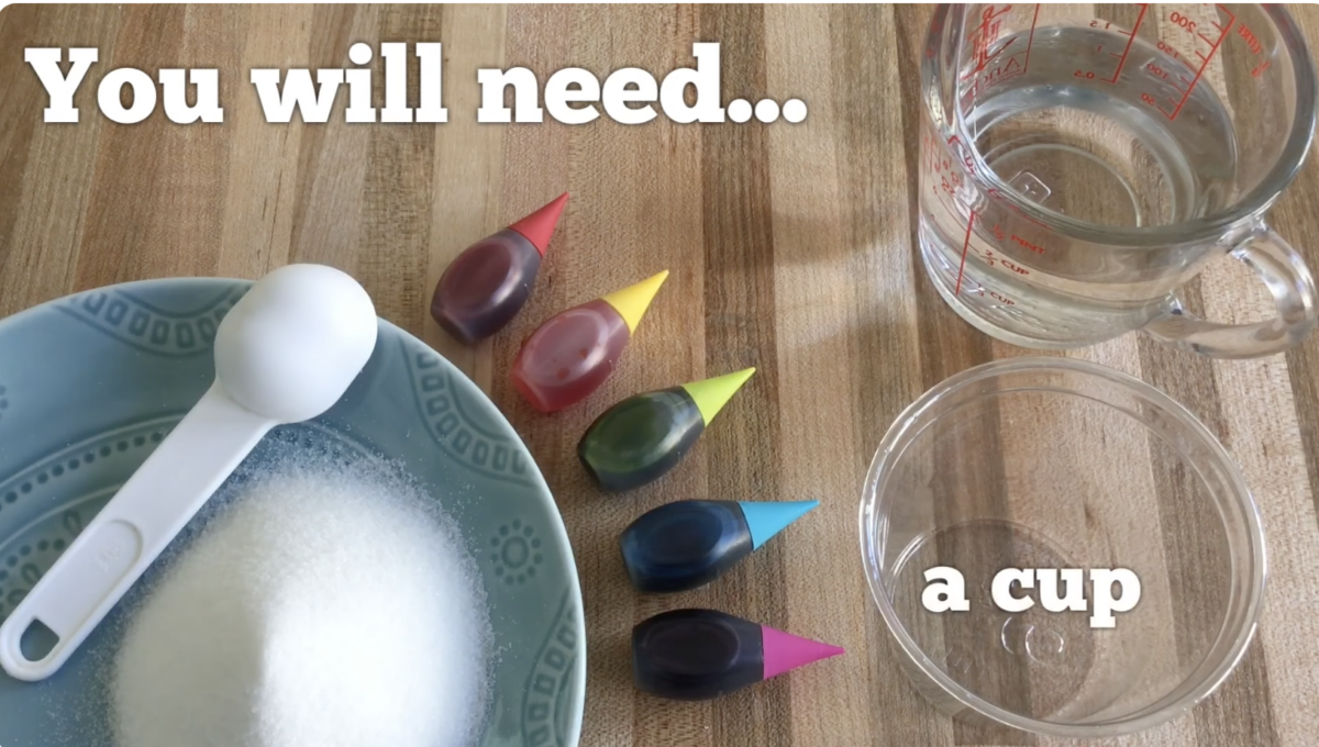 Supplies needed for a DIY art craft. Sugar, food coloring, warm water, and a clear cup. 