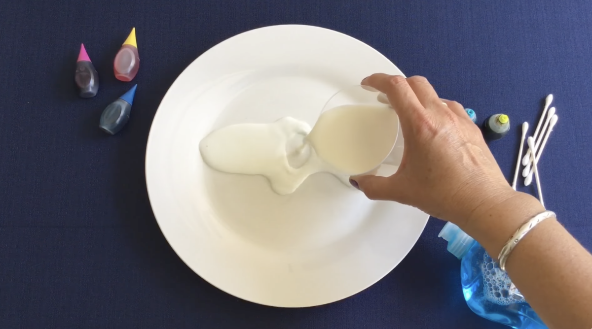 Pouring milk onto a plate for a fun colorful craft from ABCmouse. 