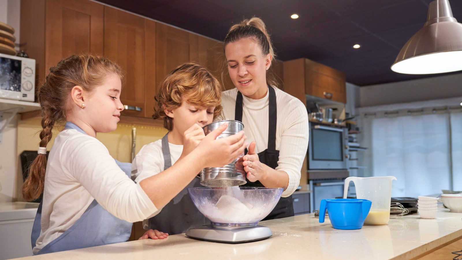 Two children baking with their mother in the kitchen. 