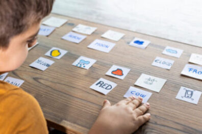 Child with word and picture flashcards laid out on the table in front of him. 