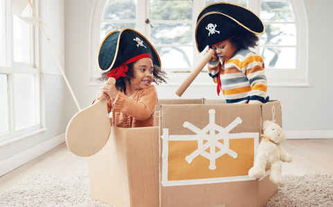 Two children playing pirates inside a box. 