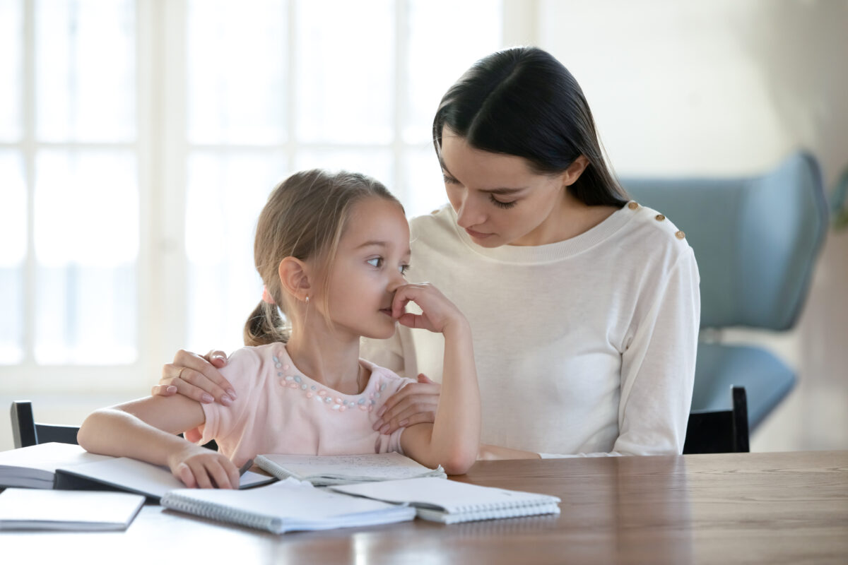 A mother comforting her daughter who feels sad because she is having a hard time learning to read. 