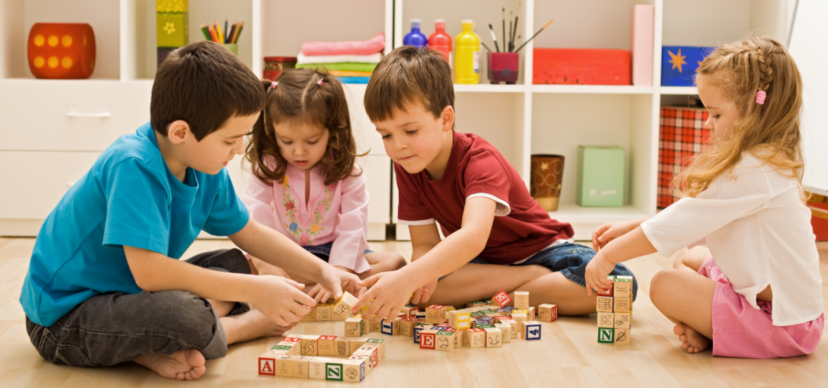 Children working together playing with a pile of blocks on the floor. 