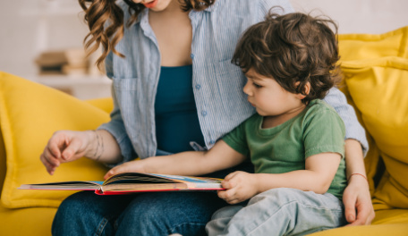 a mother and young son looking at a book together. 