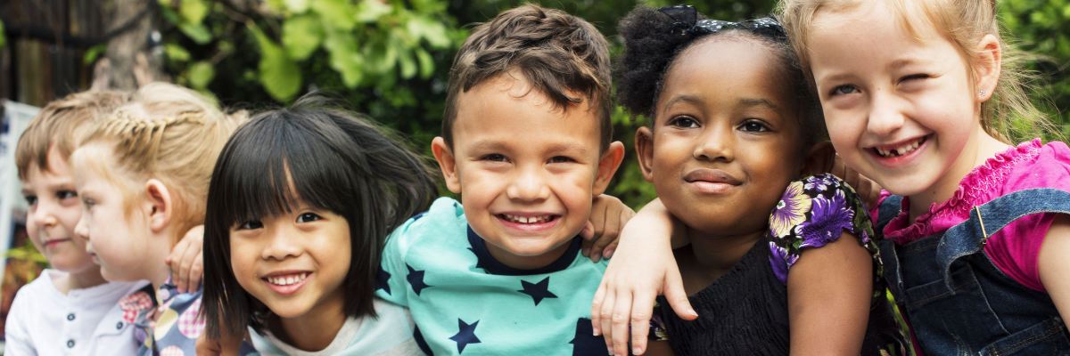 Kindergarten children smiling with their arms around each other. 