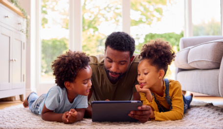 Father looking on the computer with his young daughter and son. 