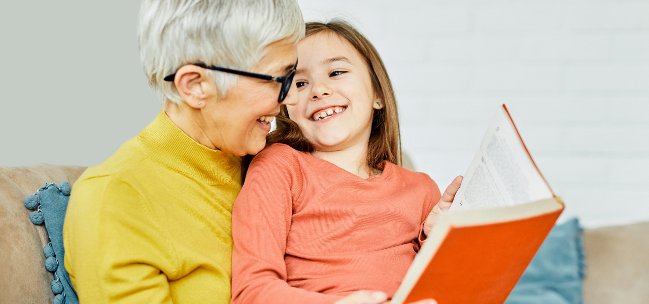 A grandmother patiently reading to her granddaughter. 