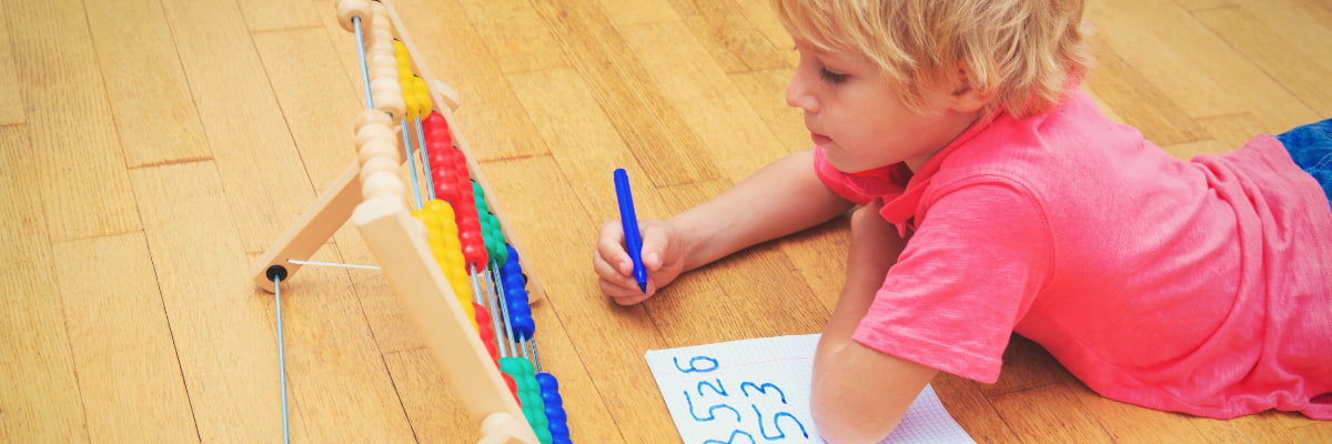 Boy using an abacus to practice counting and writing numbers. 