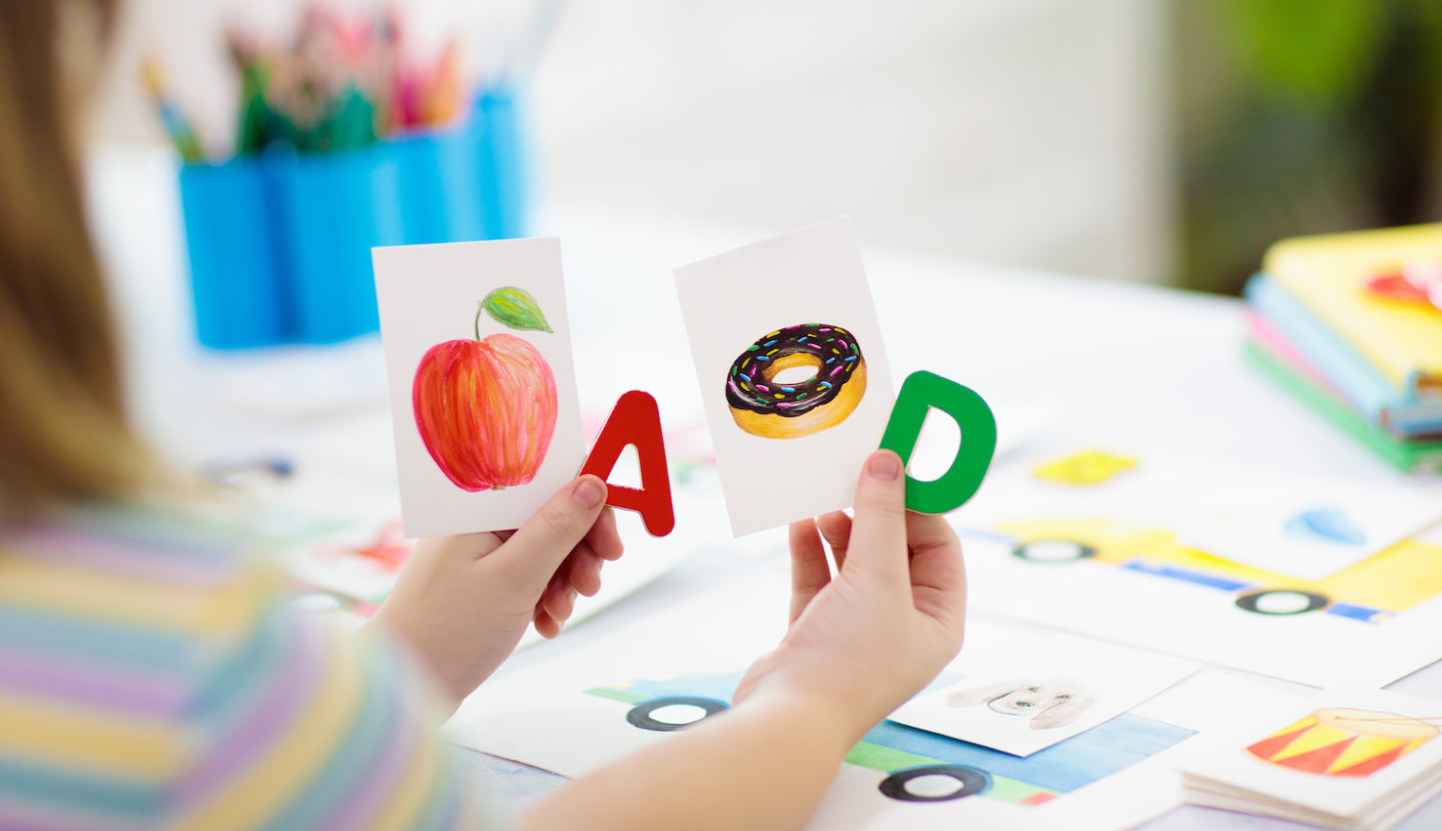 A child practicing phonemic awareness with letter and picture cards. 