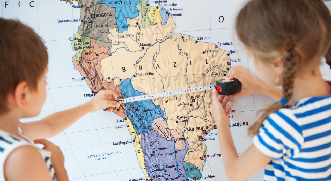 Children measuring a map with a measure tape. 