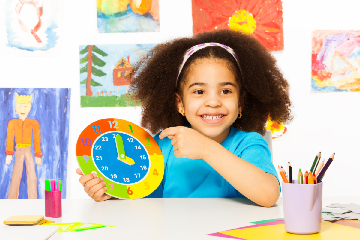 Girl pointing at a colorful clock. 