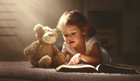 Child reading a book in the sunlight. 