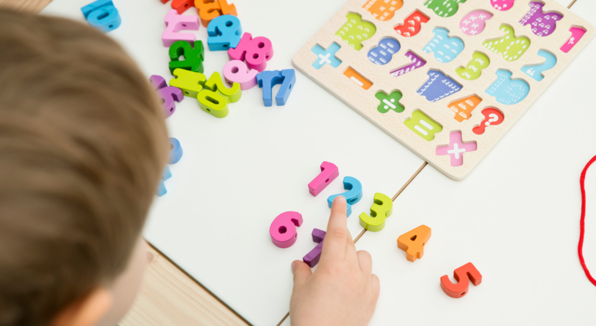 Boy using colorful wooden numbers to sequence them in order. 