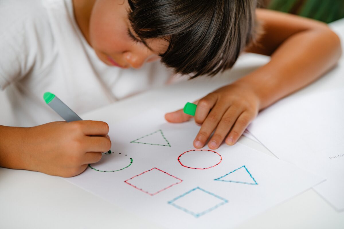 Child tracing geometric patterns to practice math concepts. 