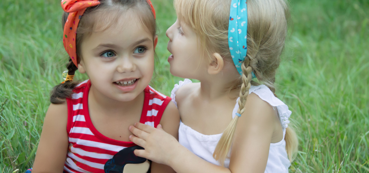 Two young girls whispering to each other. 