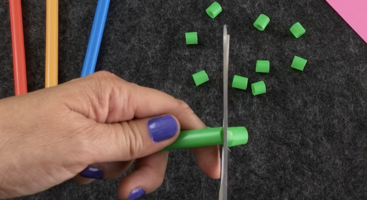A green straw getting cut into pieces. 