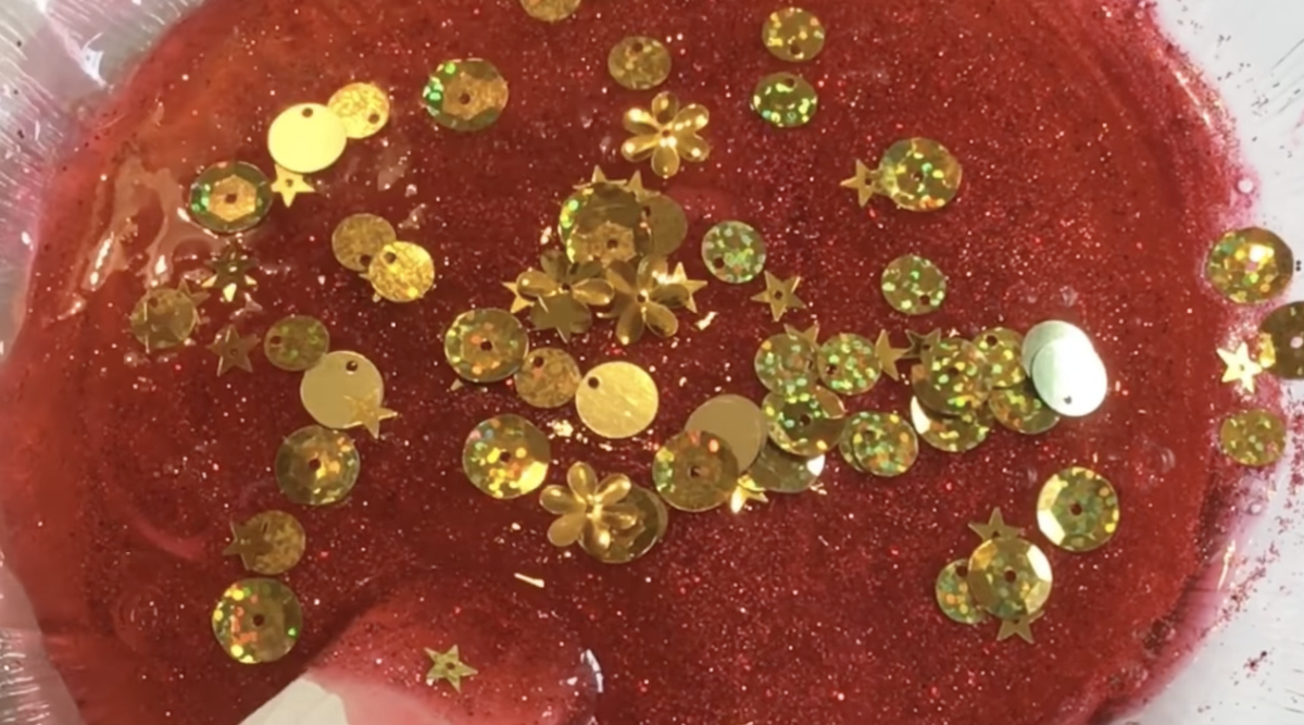 Mixing glitter and sequins into a large bowl of slime. 
