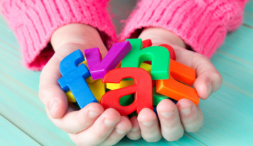 A child holding colorful letters. 