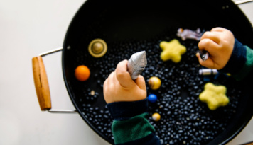 A pot of black beans with space sensory toys. 