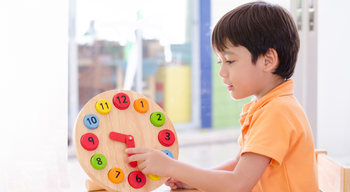 A young boy learning to tell time by using a colorful wooden clock. 
