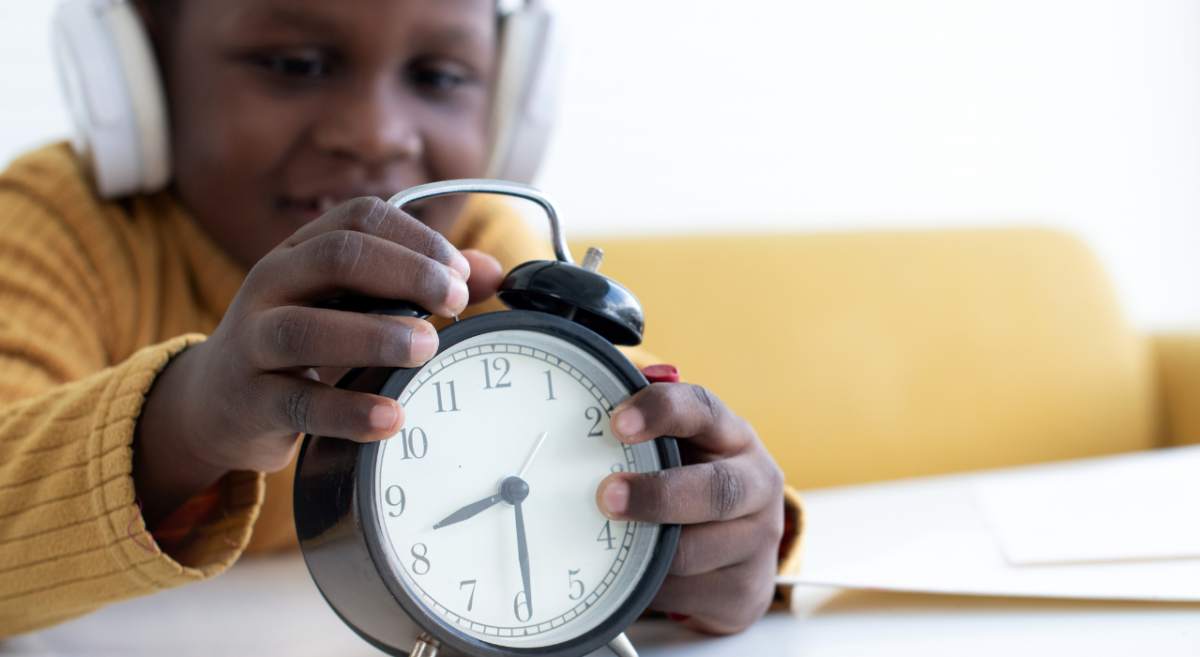 A child playing with an analog alarm clock. 