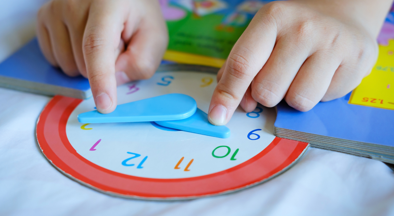 Small child hands moving the hand of a colorful looking clock. 