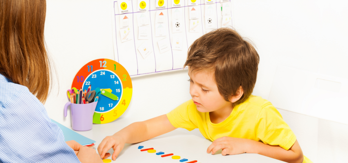 A young child working on learning how to tell time with their teacher. 