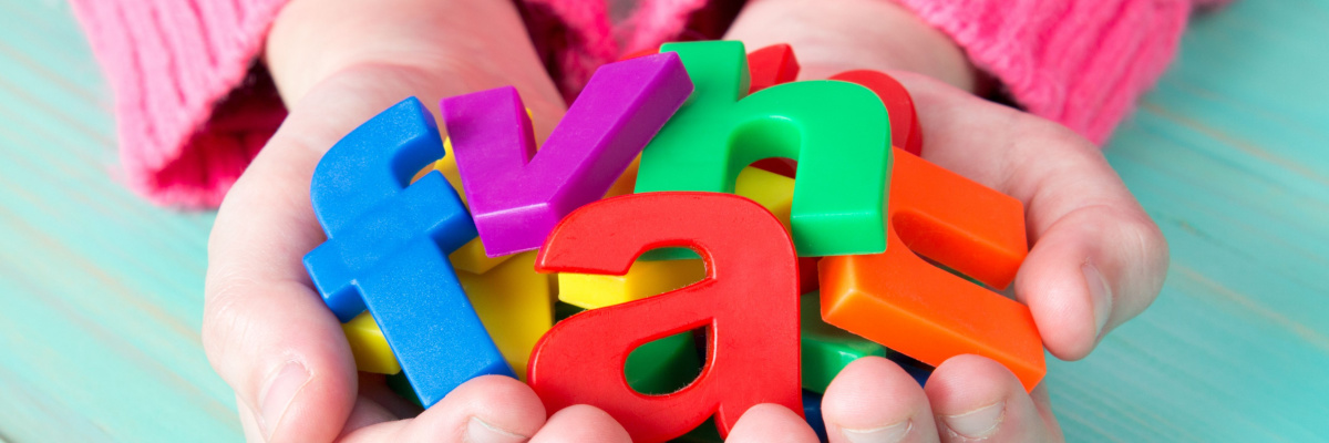 A child holding colorful plastic letters in their hands. 