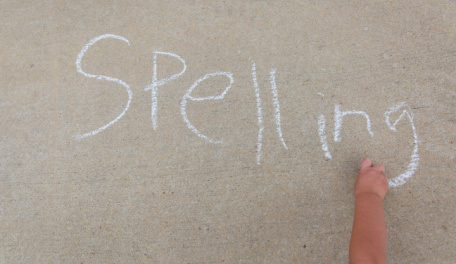 The word spelling written in blue chalk on cement. 