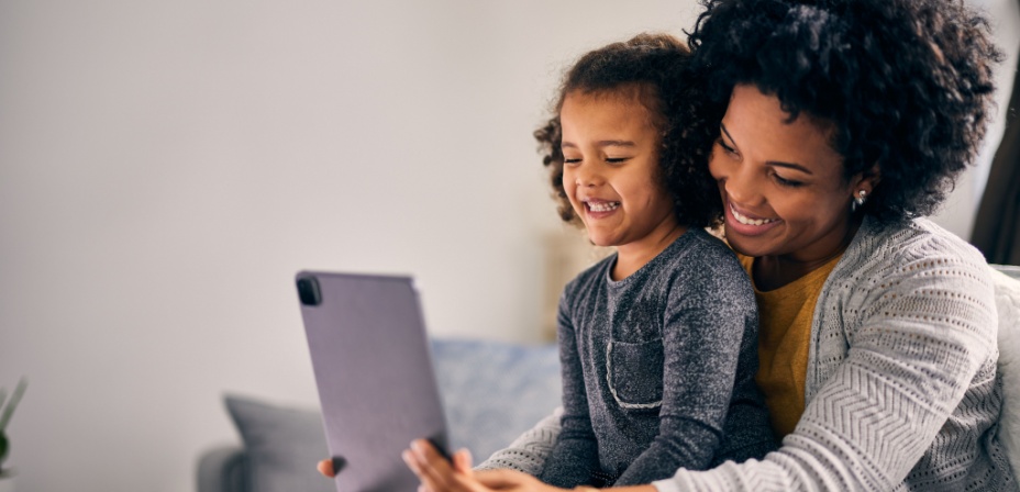 A mother and daughter learning on a digital screen together. 