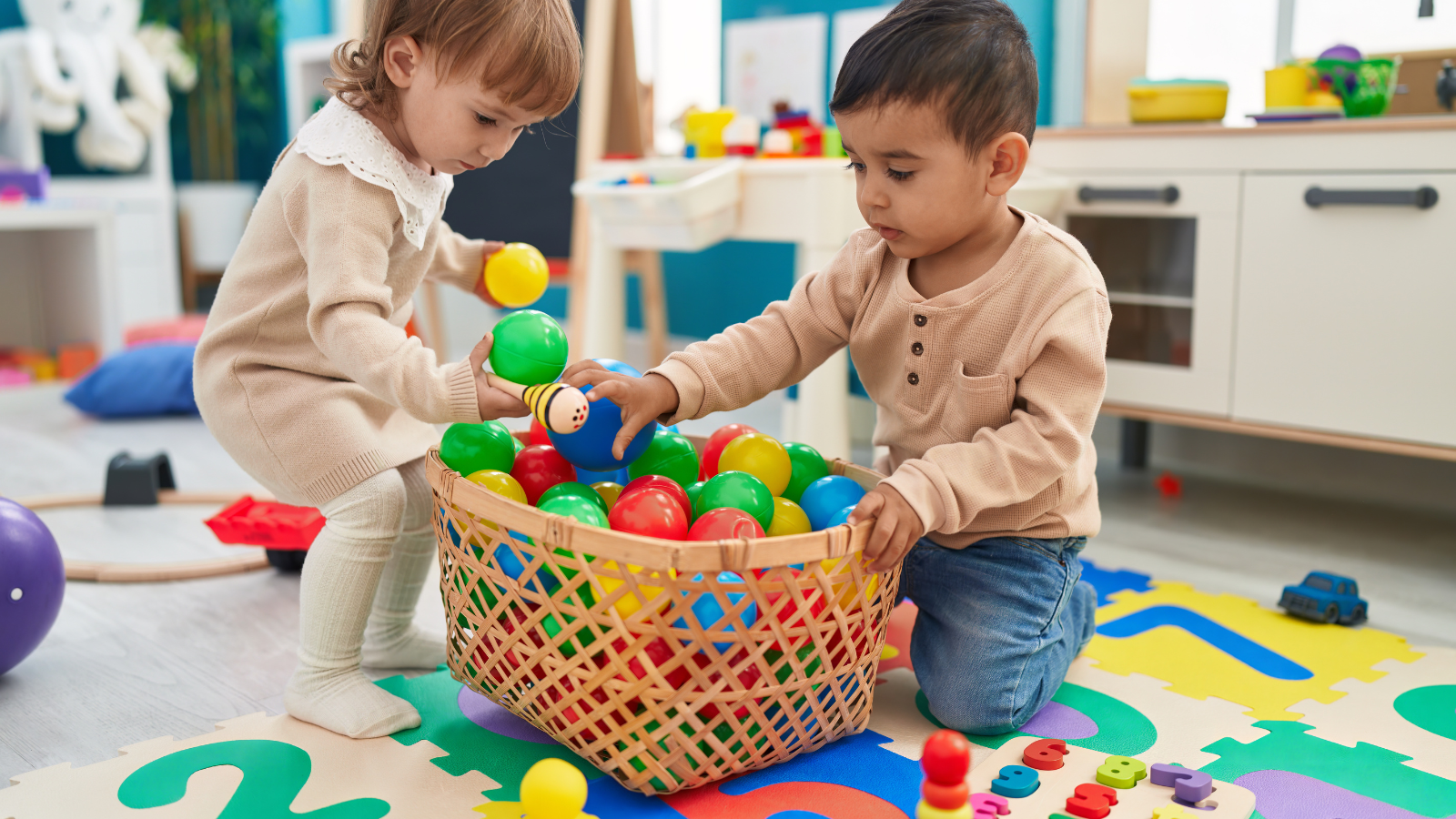Two children playing together with a bin of colorful balls. 