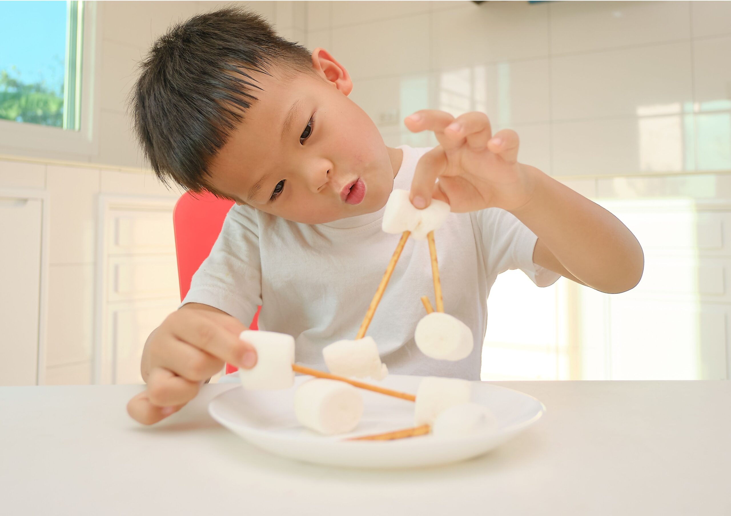 A young child playing with marshmallows and pretzels building things in this fun indoor activities.
