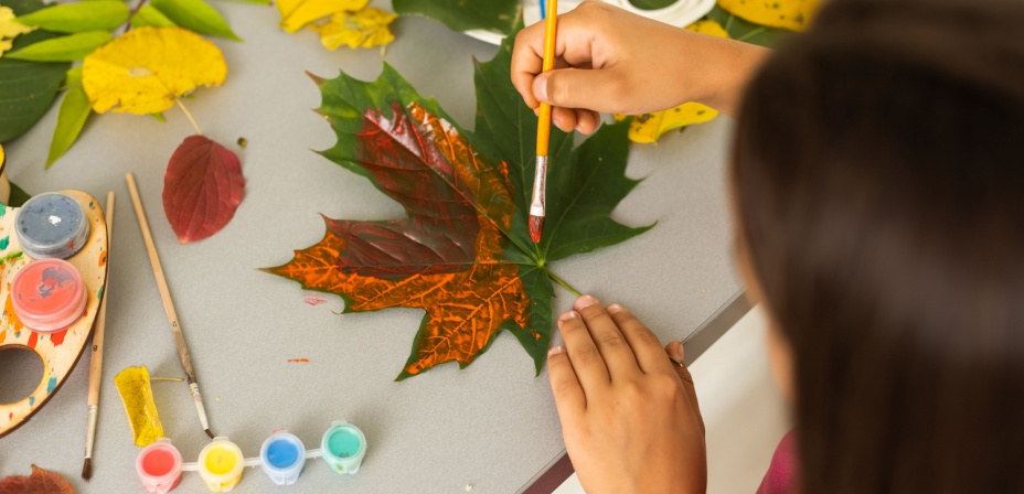 Young girl painting a green leaf orange.