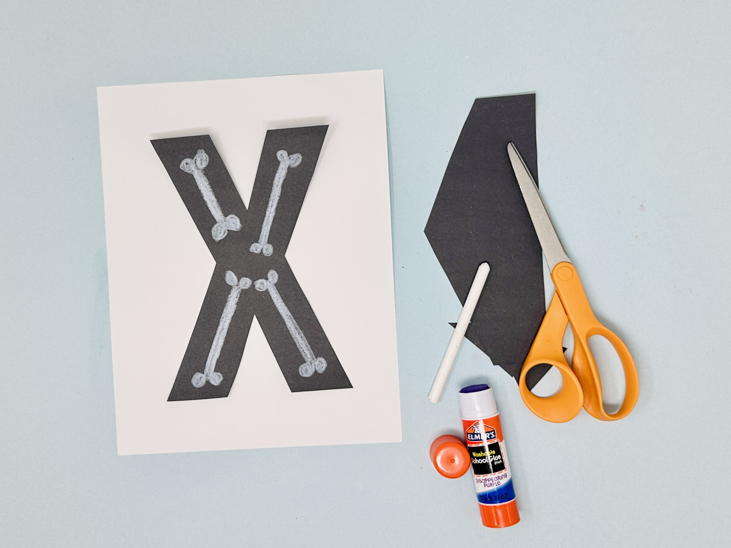 Letter X skeleton craft made with black paper and small white bone shapes.